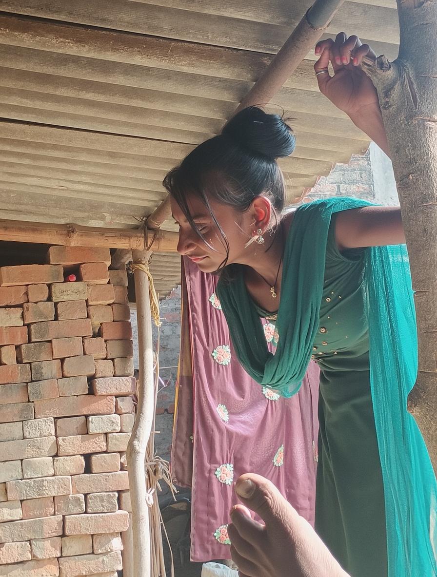 A cheerful young woman wearing a green traditional outfit with a flowy turquoise scarf, laughing joyfully while standing in a rustic setting