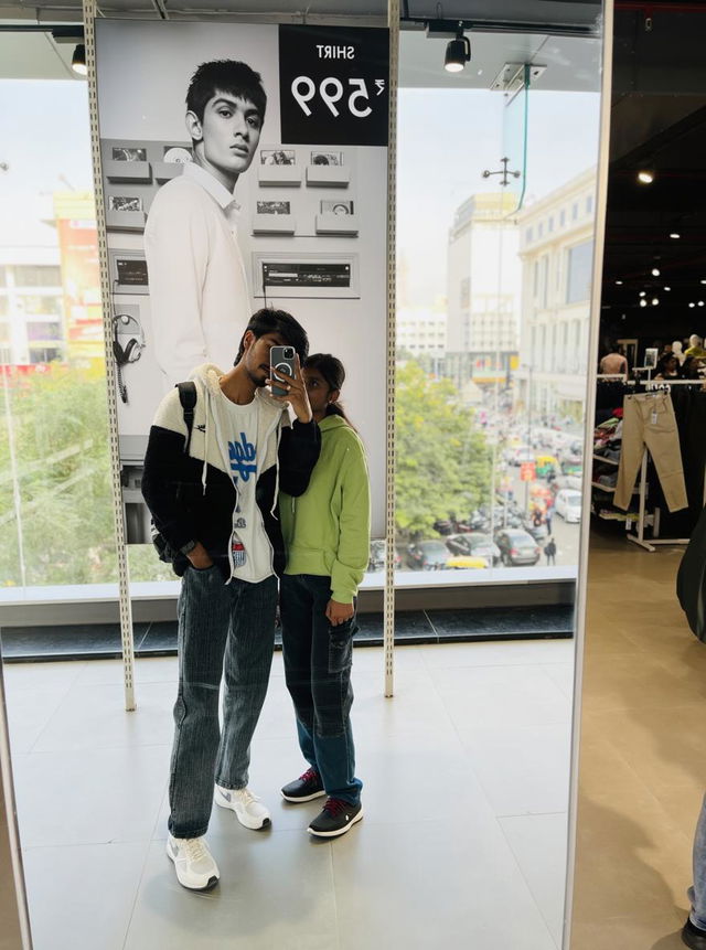 A stylish couple posing in front of a large mirror in a trendy clothing store