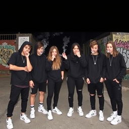A group of six teenagers dressed in black clothing with white sneakers, casually smoking together