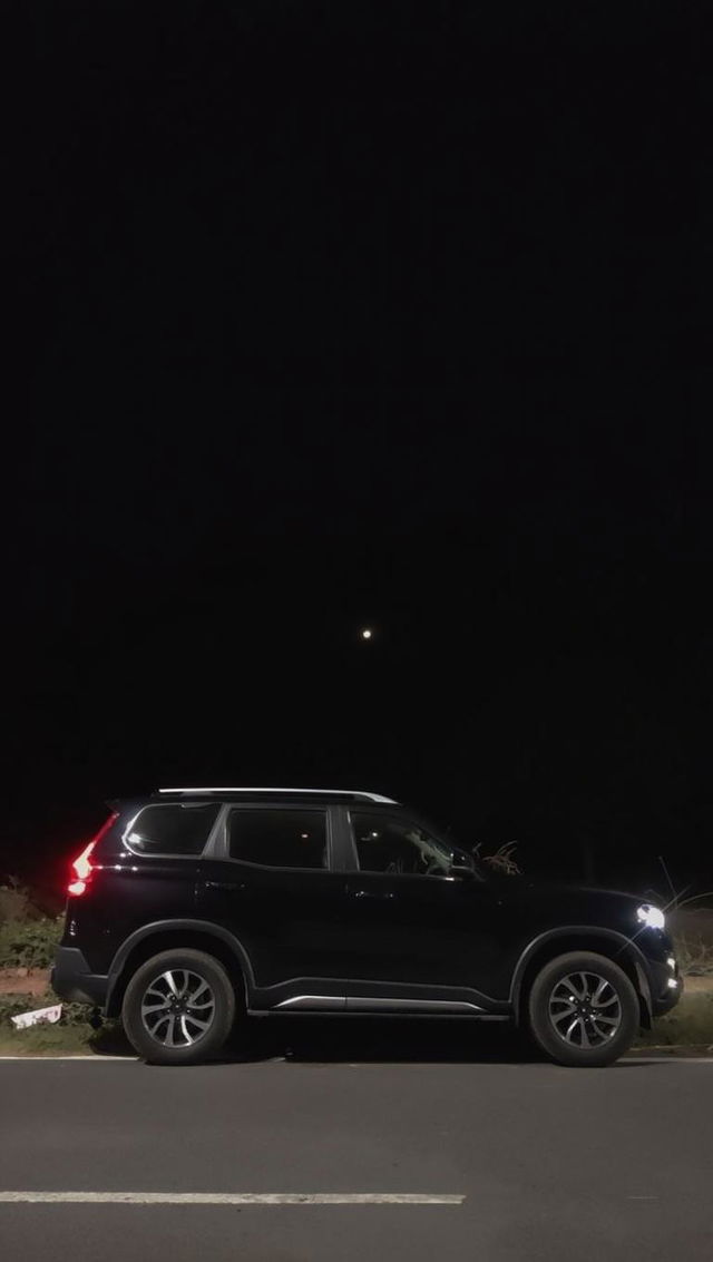 A black SUV parked on the side of a dark road