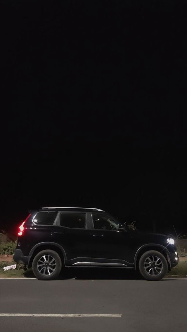 A sleek, modern black SUV parked along a dark, empty road at night