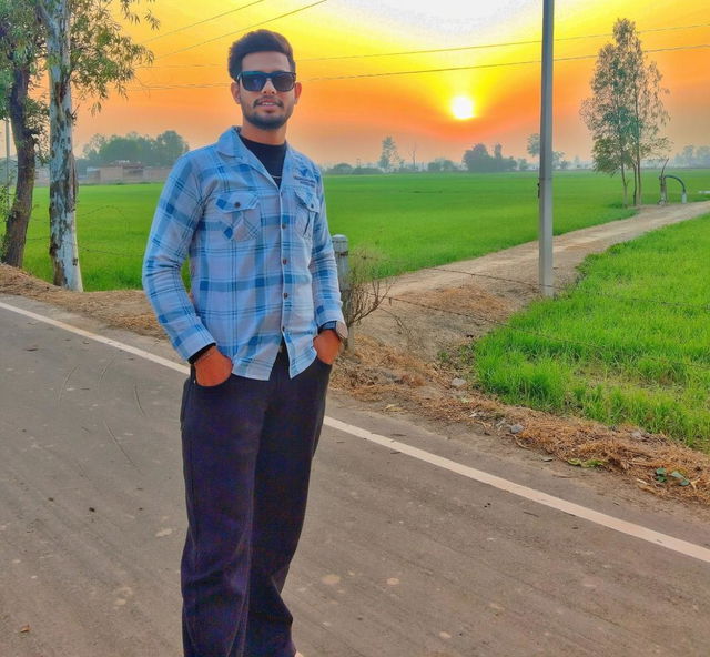 A young man standing confidently on a rural road during sunset