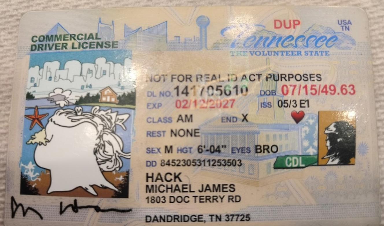 A driver's license photo featuring a male with a bald head and a serious expression