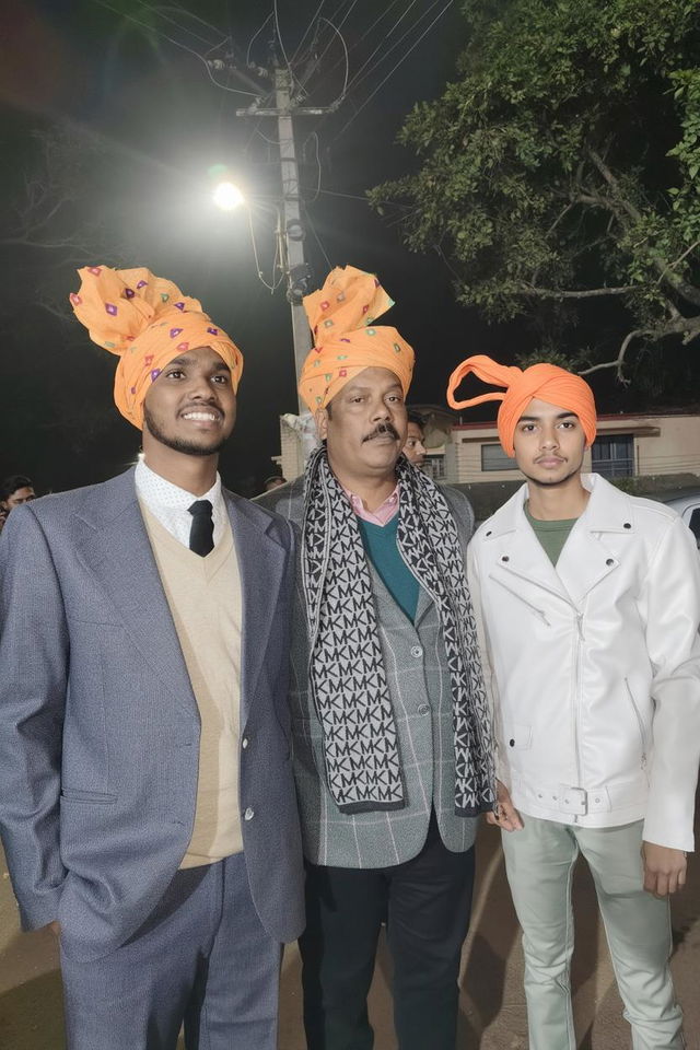 A group of three men wearing colorful traditional turbans with floral patterns, capturing a joyful moment at a night event