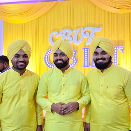 Three 27-year-old men at a vibrant yellow wedding event, dressed in traditional yellow Punjabi pajamas
