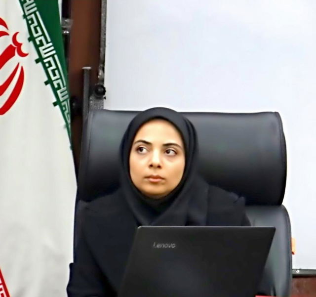 A focused woman in a formal setting, sitting at a conference table