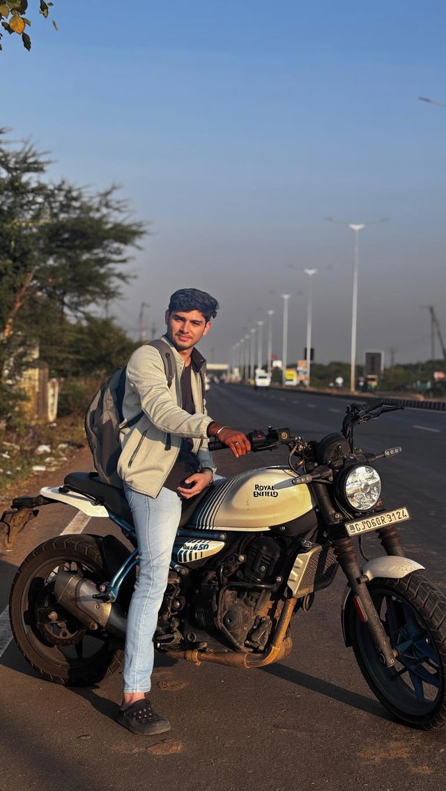 A stylish young man sitting on a motorcycle on a scenic highway