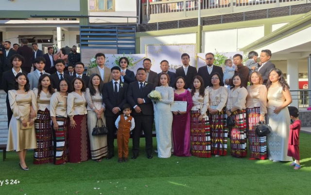 A lively group photo capturing a wedding celebration with a diverse crowd wearing elegant attire