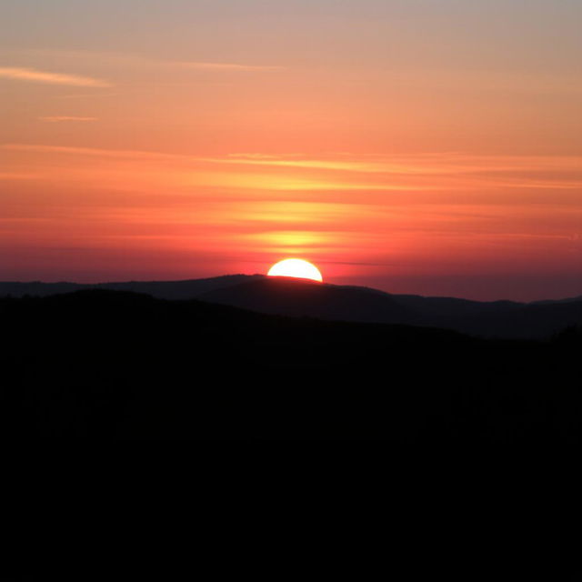 A serene landscape featuring a breathtaking sunset with vibrant hues of orange, pink, and purple in the sky, casting a warm glow over the surroundings