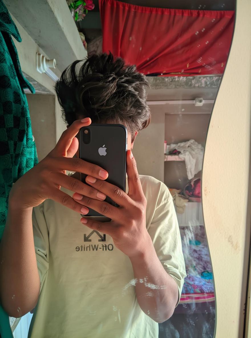 A young person taking a selfie in a mirror, reflecting a casual and relaxed atmosphere