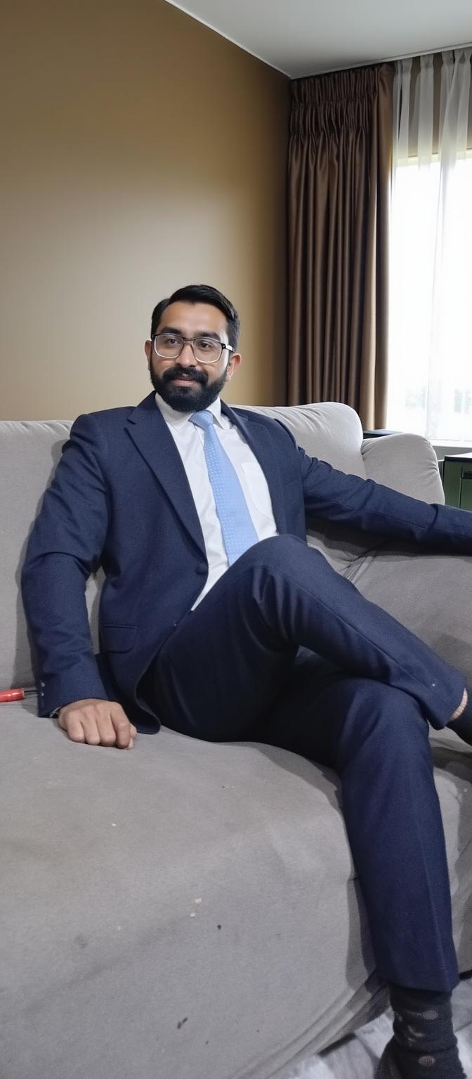 A well-dressed man in a formal suit, sitting confidently on a sophisticated sofa in a modern setting