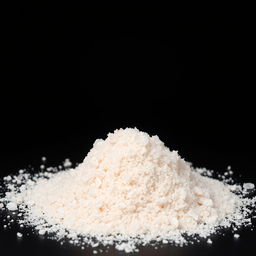 A mound of pink salt powder spread out on a black background, showcasing the delicate texture and color of the salt