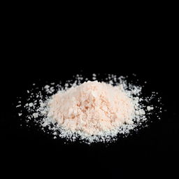 A mound of pink salt powder spread out on a black background, showcasing the delicate texture and color of the salt