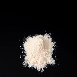 A mound of pink salt powder spilled on a flat surface, with nothing else in the image, and a completely black background