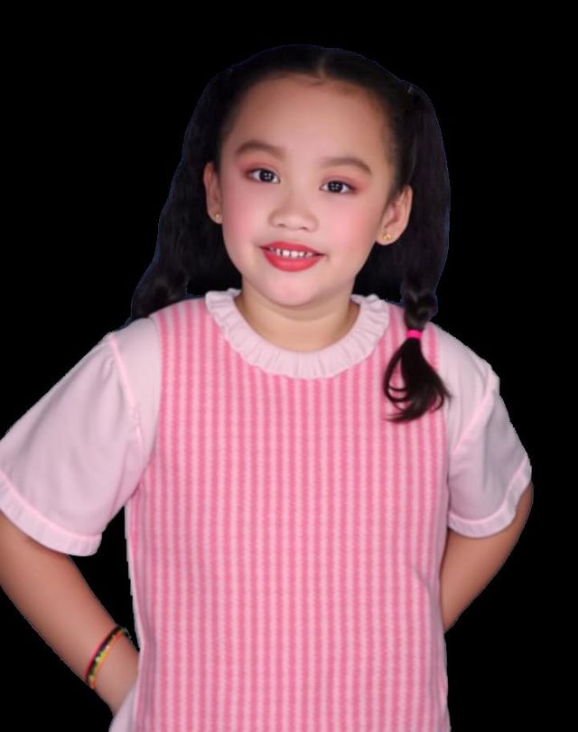 A cheerful young girl wearing a pink dress, standing confidently with her hands on her hips