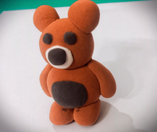 A cute, cartoonish brown bear figure made of modeling clay