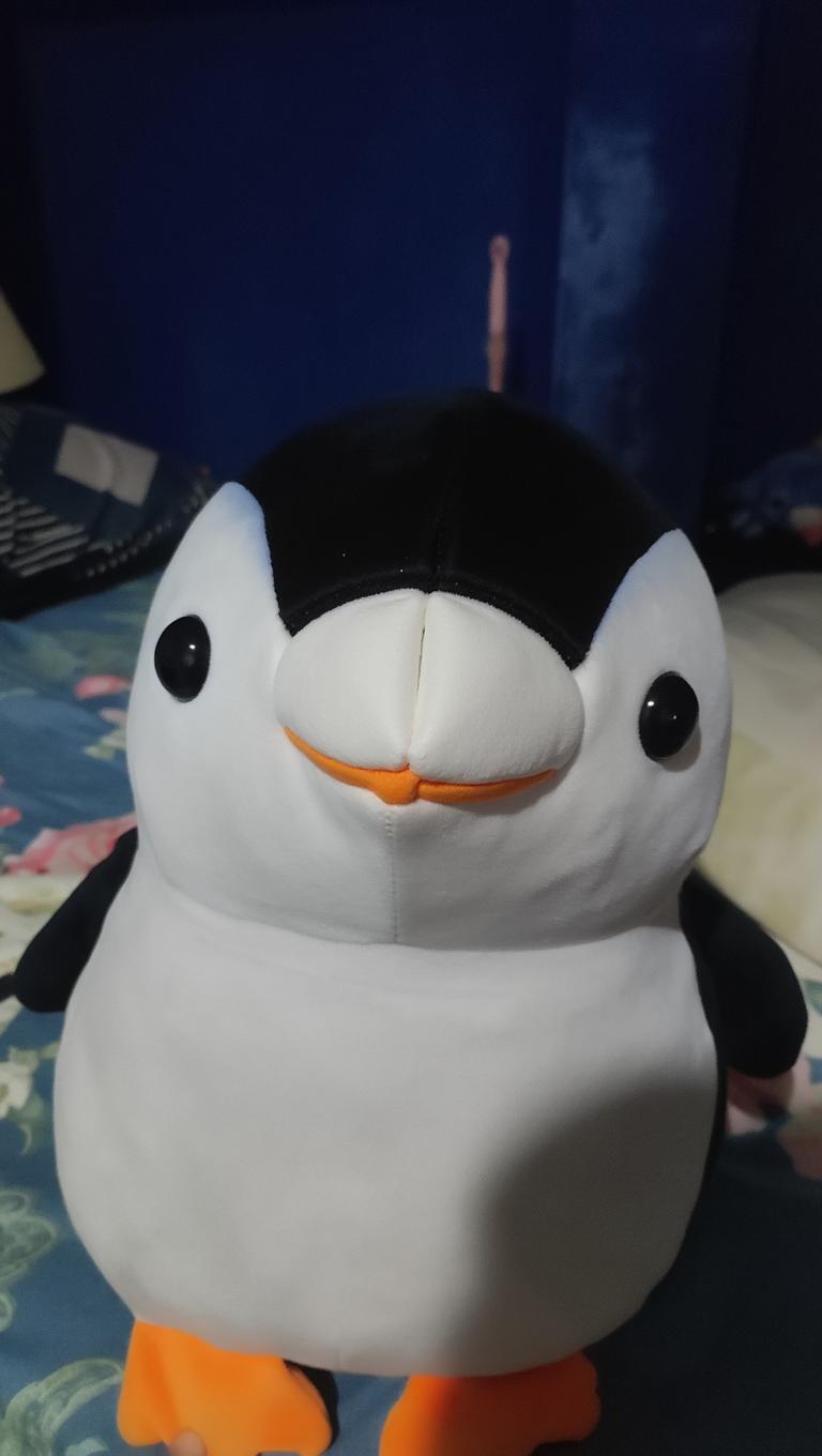 A cute plush penguin with a round body, soft black and white fur, and an orange beak