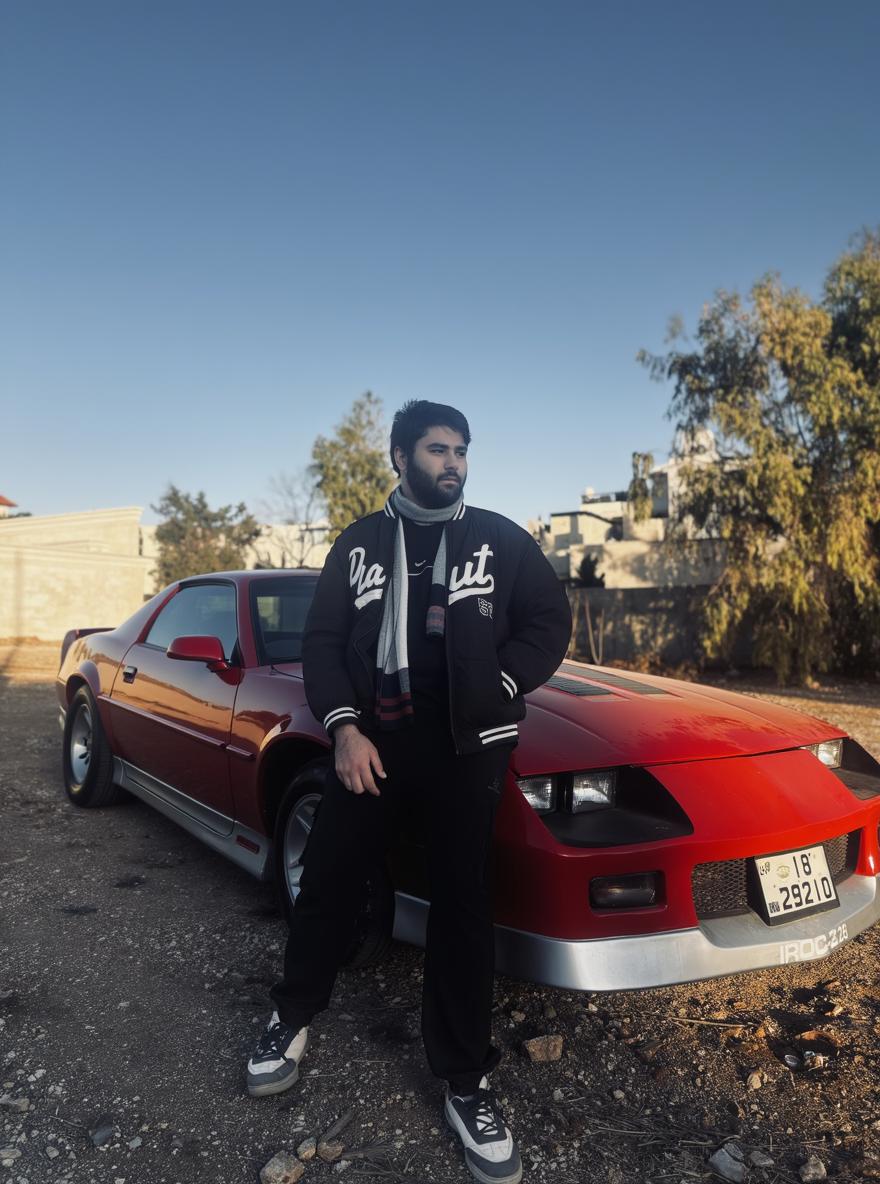 A stylish young man standing confidently next to a classic red sports car in a rugged, urban environment