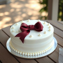 A beautifully decorated white round cake with a rich burgundy bow artfully placed on top