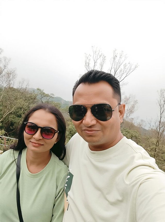 A candid outdoor portrait of a couple enjoying nature, with a lush green landscape in the background