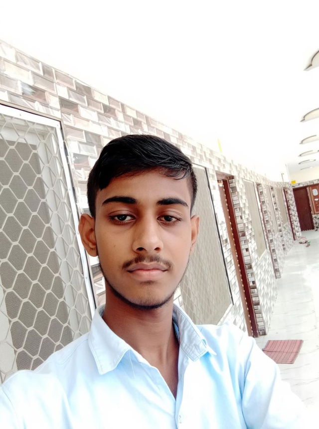 A teenage boy with a confident expression, wearing a stylish light blue shirt