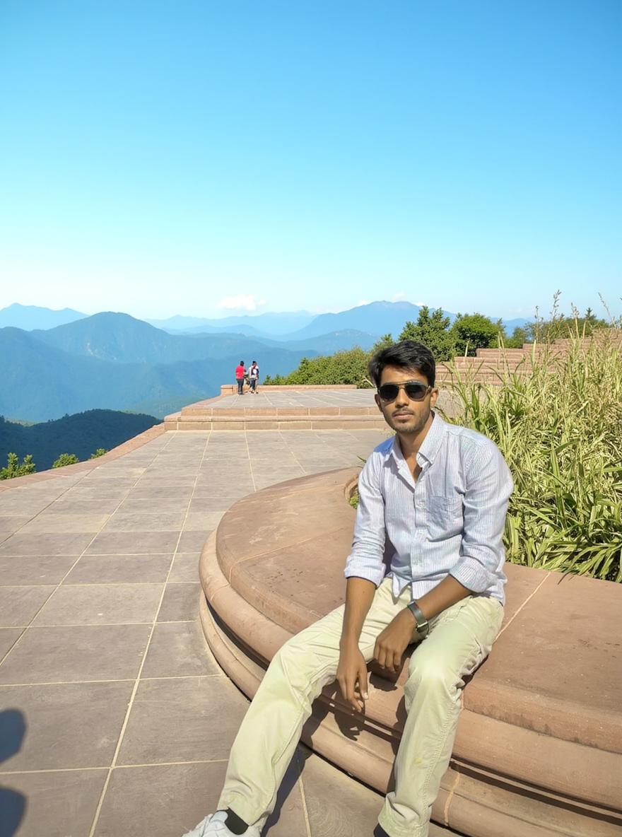 A man casually sitting on a beautifully designed stone bench in a public space, with a striking monument in the background