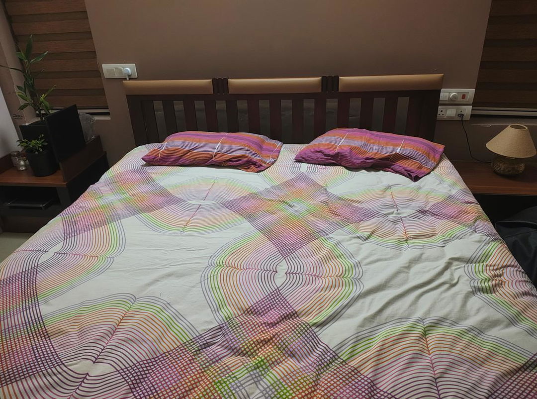 A cozy bedroom scene featuring a neatly made bed with a colorful, patterned bedsheet and two fluffy pillows