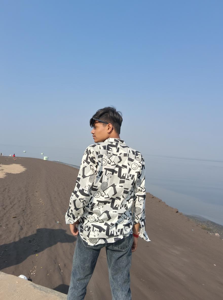 A young person standing with their back facing the camera, overlooking a calm sea on a serene beach