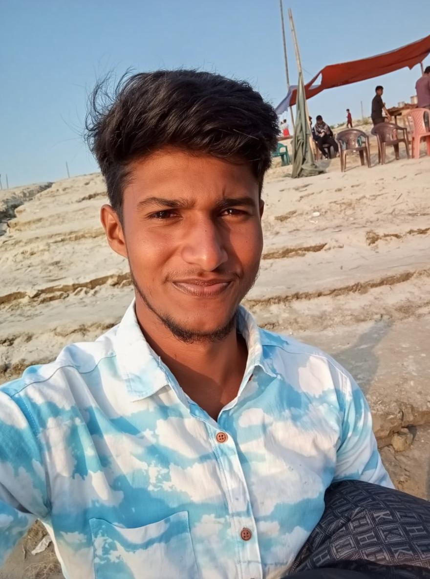 A young man taking a selfie at the beach during sunset