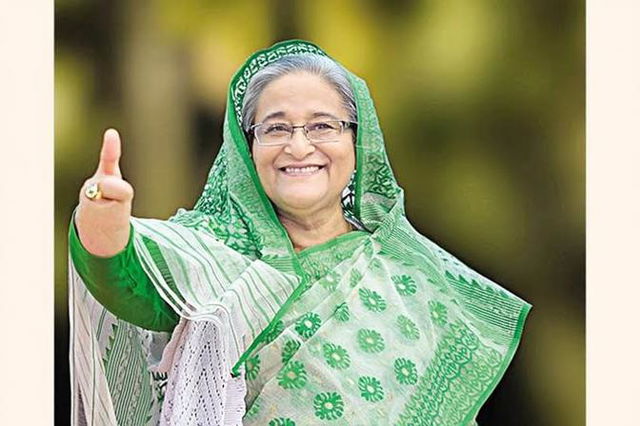 A cheerful woman waving with a warm smile, dressed in a vibrant green traditional outfit with intricate patterns, featuring a matching scarf