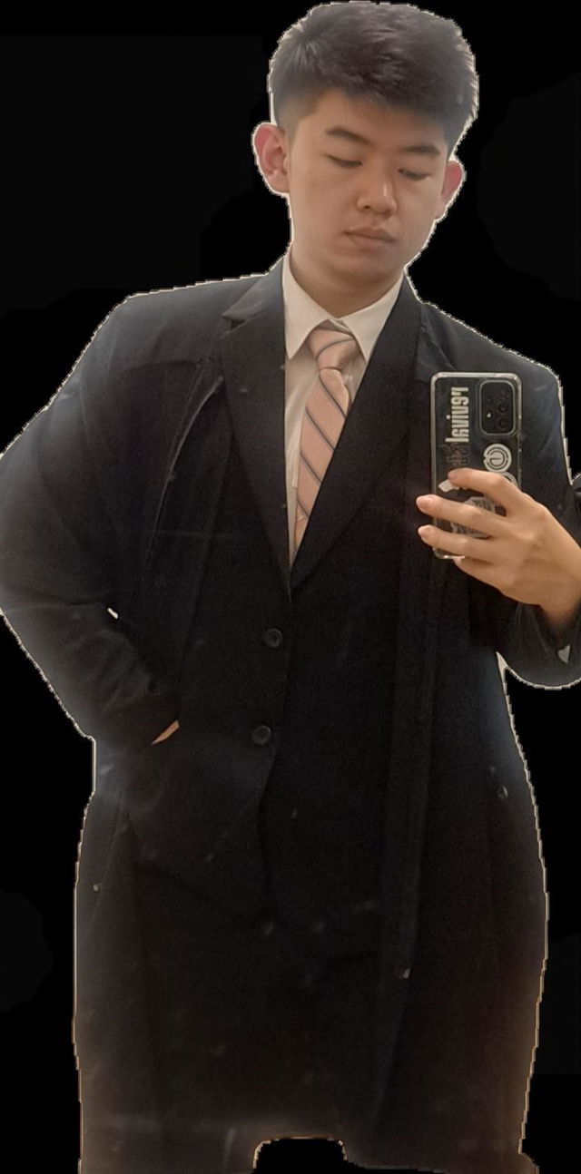 A young man in a stylish black suit with a light pink tie, posing confidently while holding a smartphone for a selfie