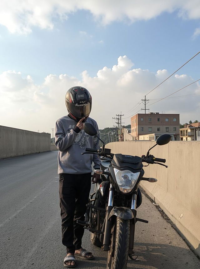 A person wearing a motorcycle helmet stands beside a black motorcycle on an empty road