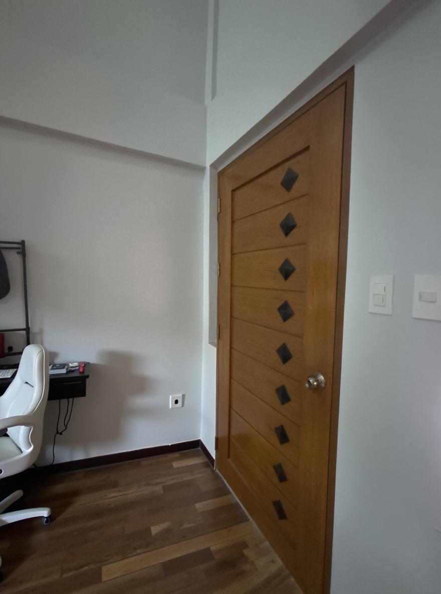 A cozy room interior featuring a modern desktop computer setup next to a wooden door