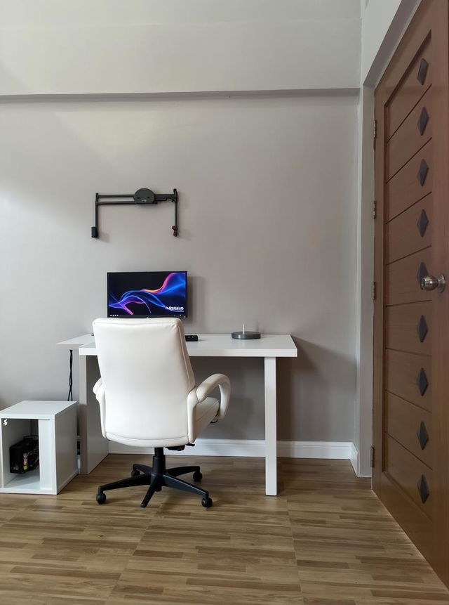 A bright and minimalistic indoor space with a long table featuring a computer desktop setup, showcasing a sleek monitor, keyboard, and mouse