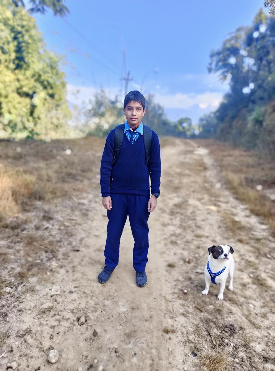 A young boy standing on a dirt path surrounded by trees and nature