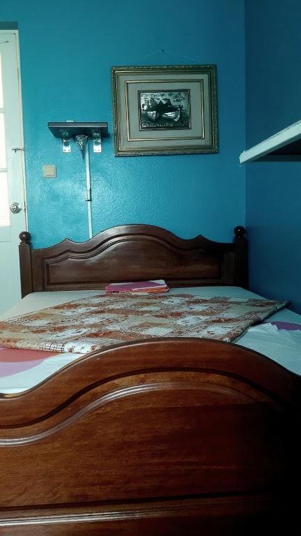 A cozy bedroom with a wooden bed featuring a richly patterned floral bedspread in shades of red and orange
