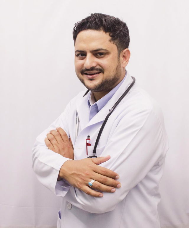 A friendly and approachable male doctor in a white coat, smiling confidently while crossing his arms