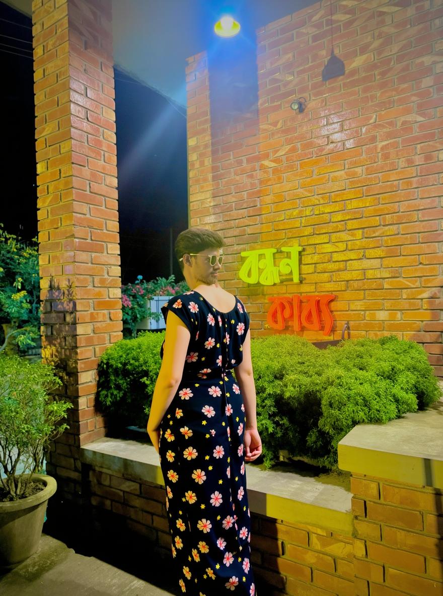 A stylish young man standing casually in front of a brick building at night