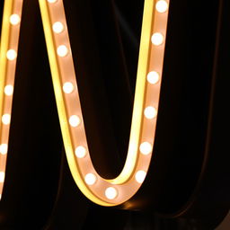 A close-up of a large, illuminated letter sign in a stylish, modern font, showcasing the letter 'W' in vibrant neon colors against a dark background