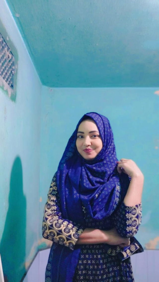 A woman wearing a vibrant blue hijab and an ornate traditional outfit