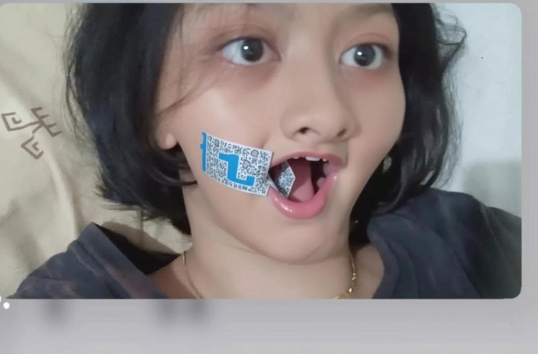 A close-up portrait of a girl with a concerned expression, her mouth covered with silver duct tape