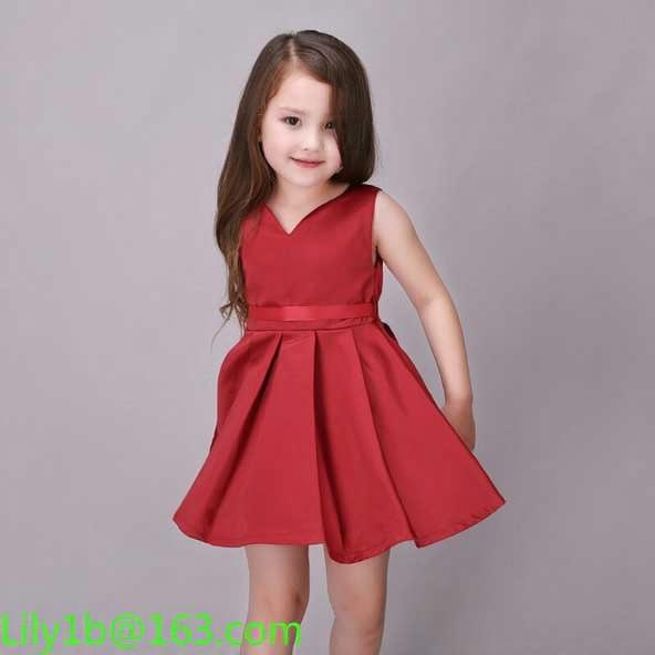 An elderly woman with a kind expression, wearing a stylish burgundy dress that resembles vintage fashion