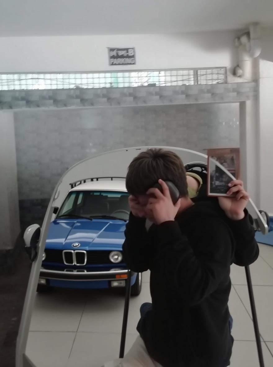 A young person in a casual black hoodie, sitting on a sleek white BMW car in a parking garage