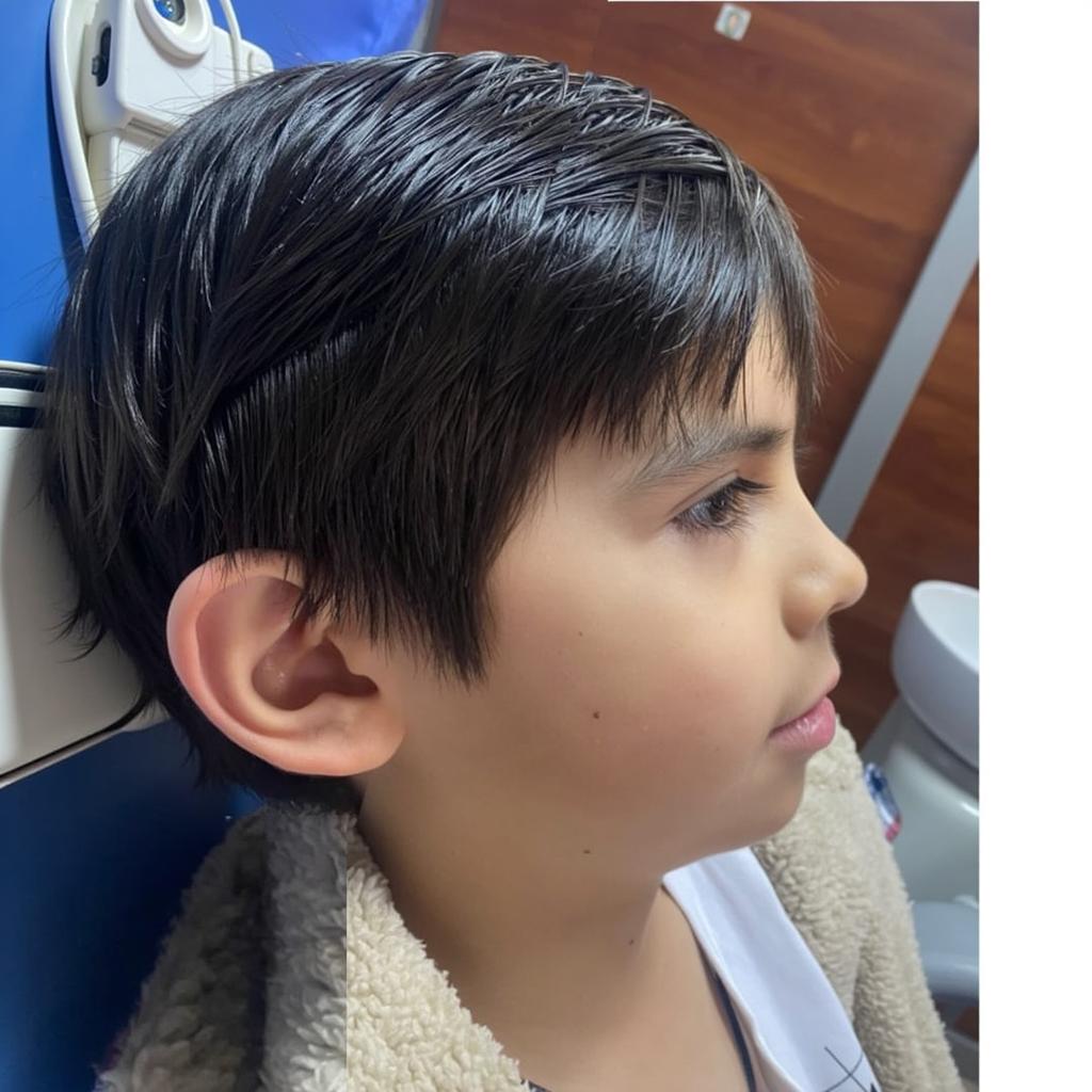 A professionally edited side profile of a young boy sitting in a cozy, well-lit environment