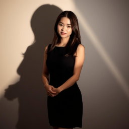 A beautiful Korean woman standing with her hands folded in front of her chest, wearing a black sleeveless dress that highlights her elegant and simple style