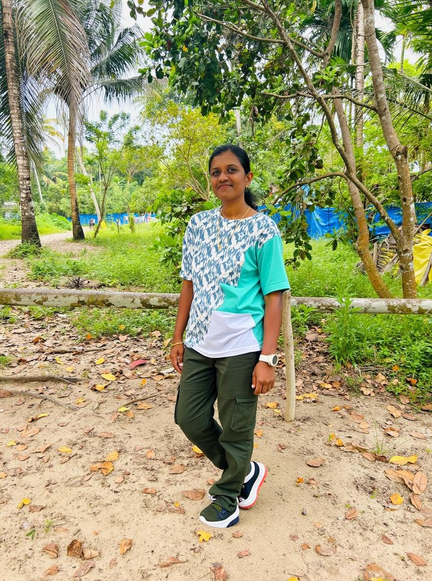 A woman standing in a serene outdoor setting surrounded by lush greenery and trees