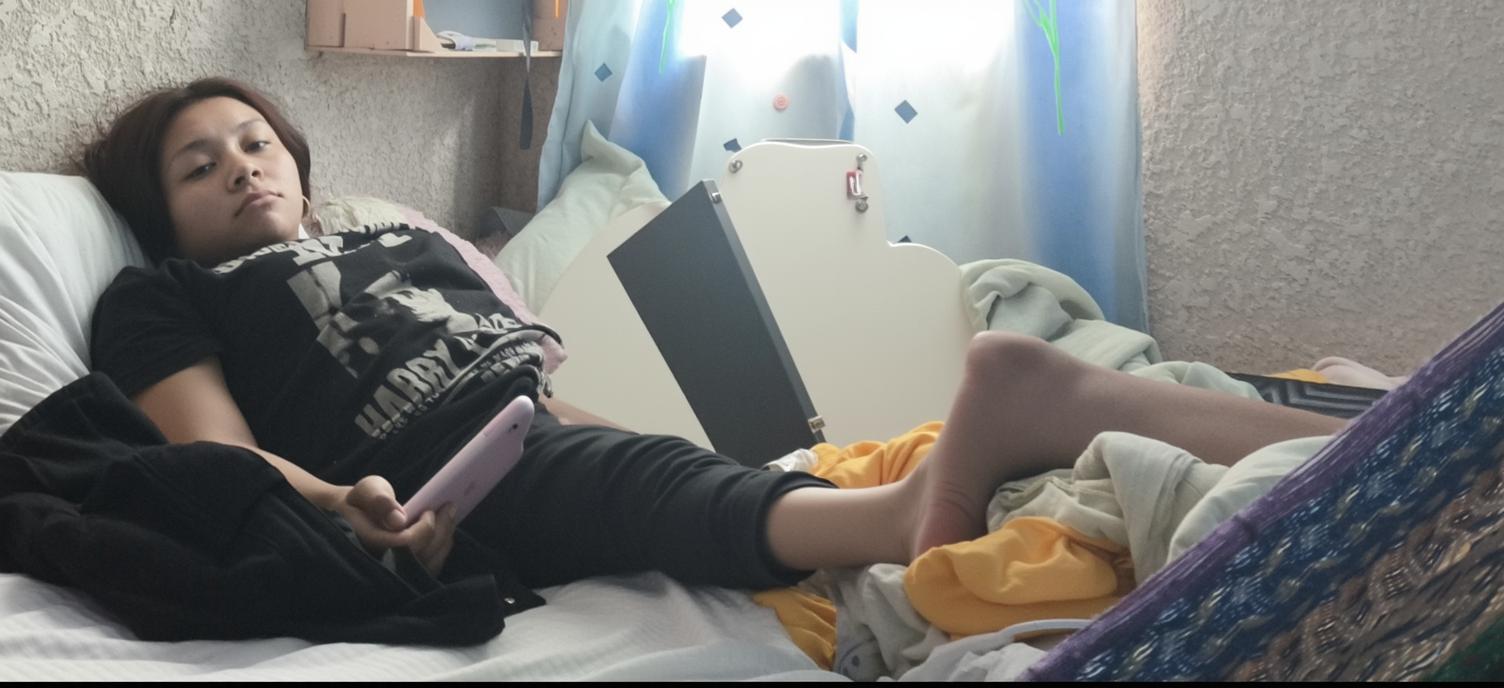 A relaxed young woman lying on a messy bed, with her legs comfortably positioned and one leg raised