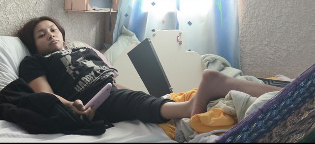 A relaxed young woman lying on a messy bed, with her legs comfortably positioned and one leg raised