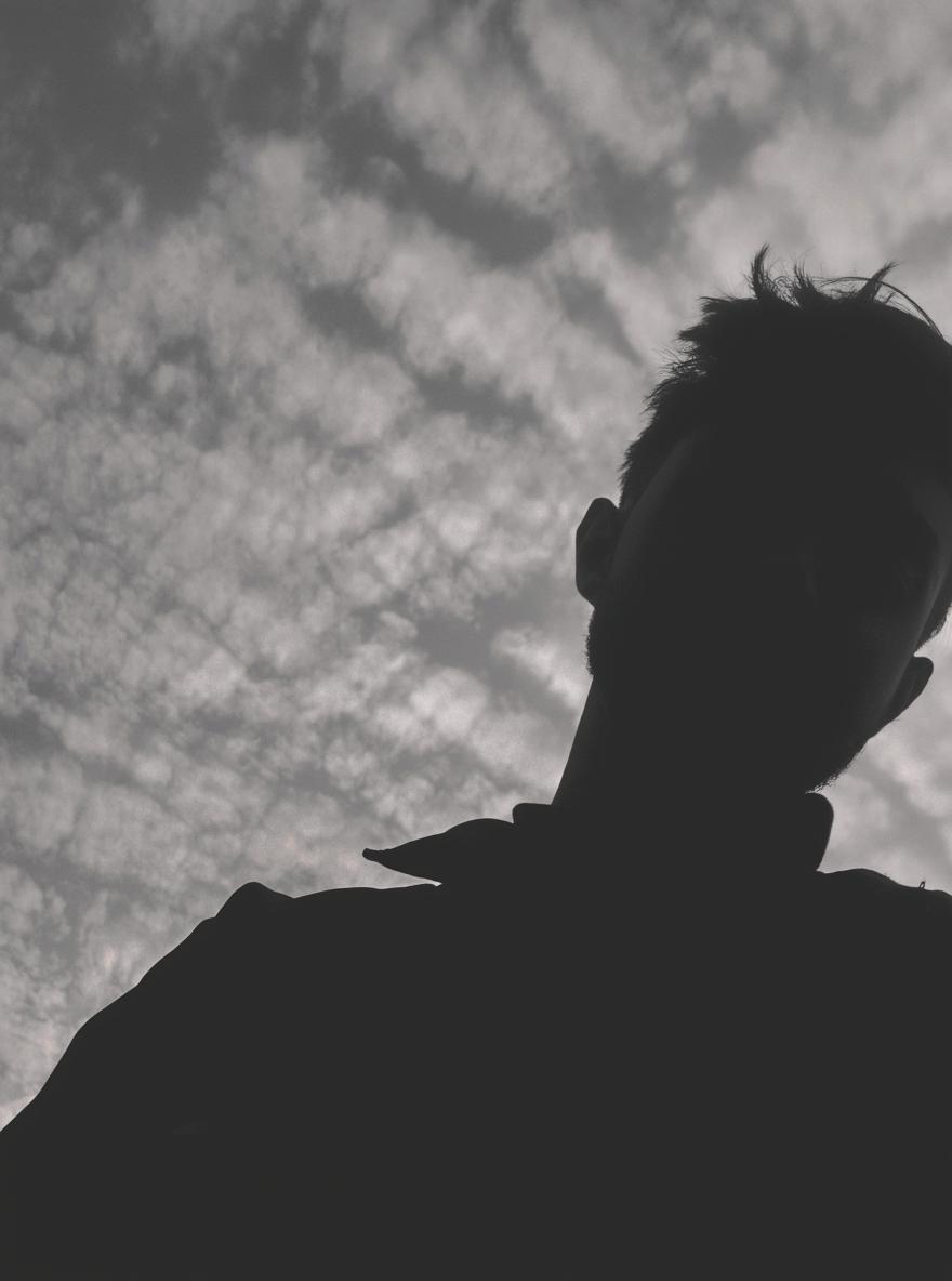 A dramatic silhouette of a person standing against a cloudy sky at dusk