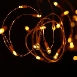 A collection of beautiful copper wire string lights glowing warmly against a dark background
